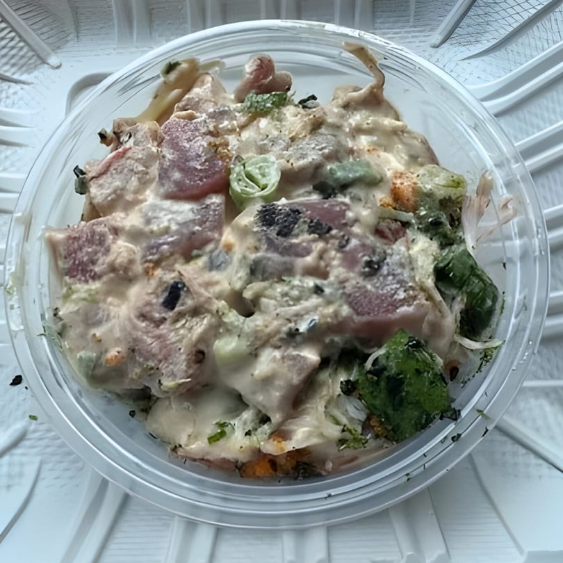 A close-up overhead view of a Poke Etc. poke bowl with creamy sauce and various toppings.